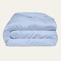 Light blue comforter folded on a beige background