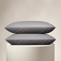 Two gray pillows stacked on a beige pedestal against a beige background