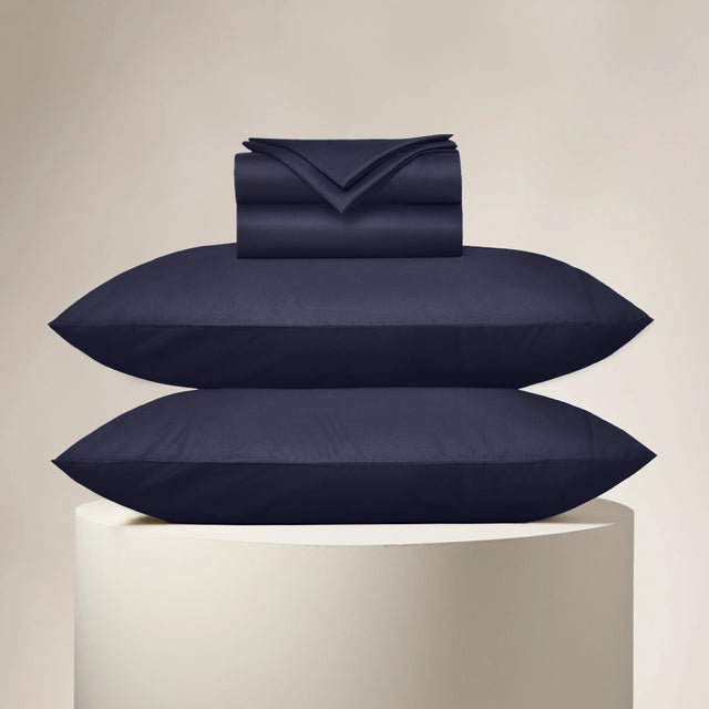 Navy blue bedding set including pillows and a duvet on a beige background