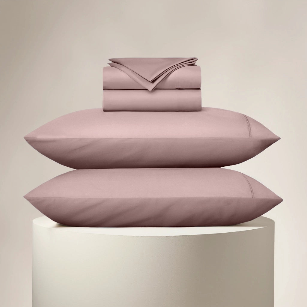 Stack of pink bedding on a beige background