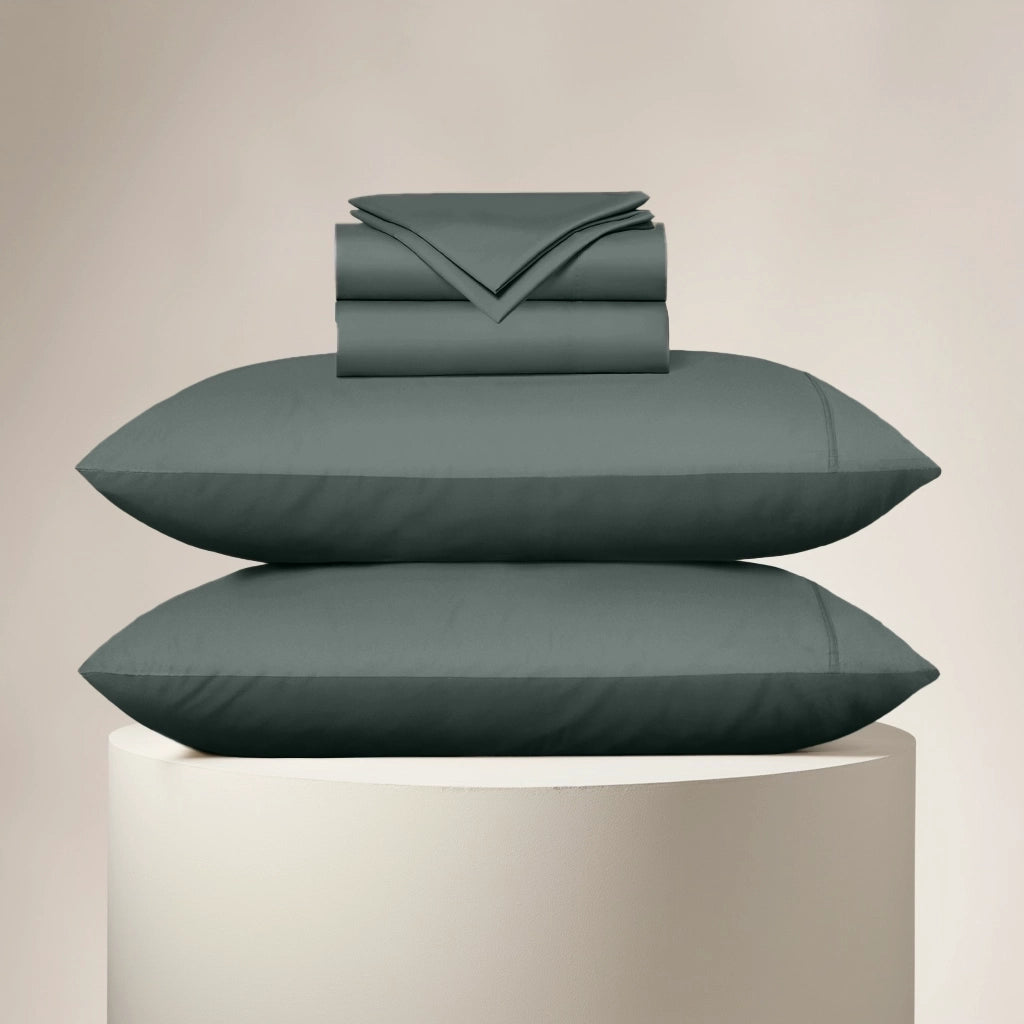 Teal bedding set including a duvet, two pillows, and a folded sheet on a beige background