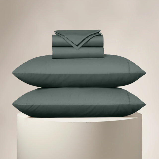 Teal bedding set including a duvet, two pillows, and a folded sheet on a beige background