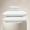 Stack of white pillows and a folded sheet on a beige background
