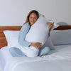 Woman holding a large pillow in a bedroom setting