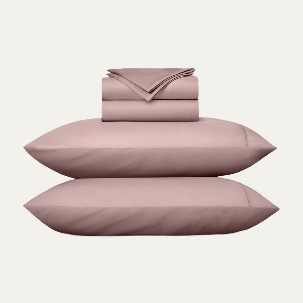 Pink bed sheet set with two pillows on a white background