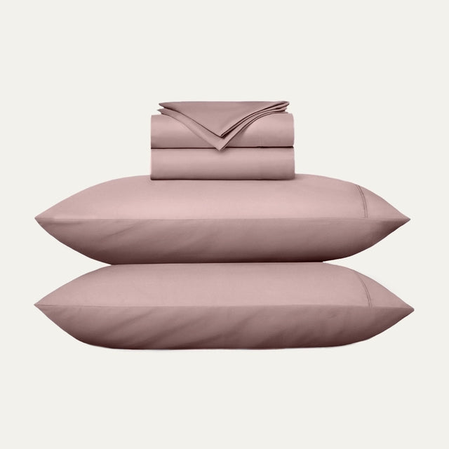 Pink bed sheet set with two pillows on a white background