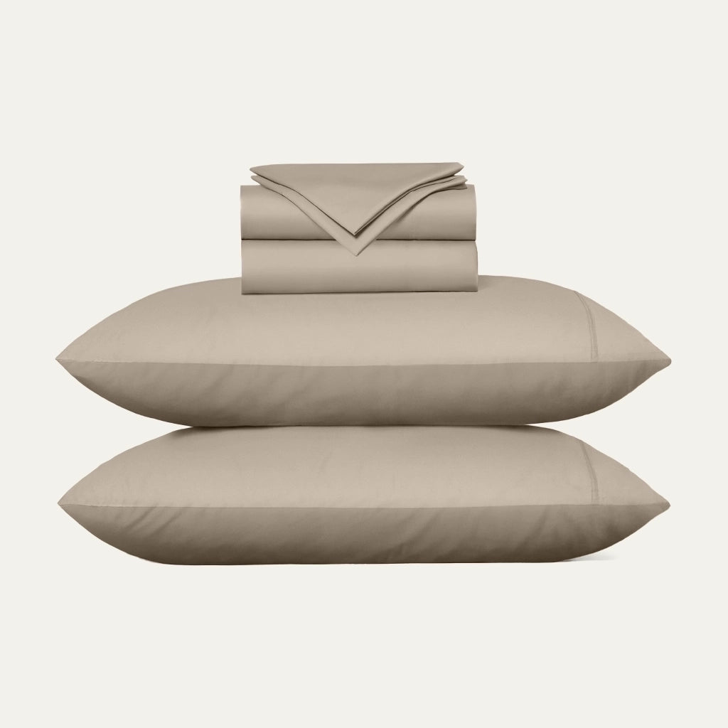 Beige bed sheets and pillows on a white background