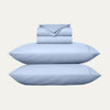 Set of light blue bedding including pillows and a folded sheet on a white background