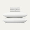 Set of white pillows and a folded blanket on a light gray background