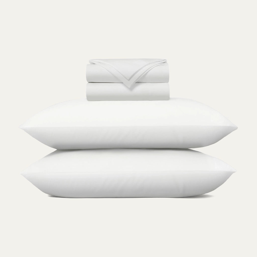 Set of white pillows and a folded blanket on a light gray background