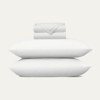 Set of white pillows and a folded blanket on a light gray background