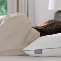 Person lying on a couch with a pillow featuring a brand label.