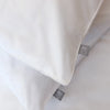 Close-up of a white pillow with a brand label on a light gray background