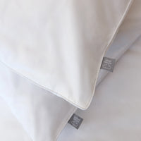 Close-up of a white pillow with a brand label on a light gray background