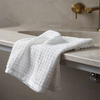 White textured towel draped over a marble countertop with a gold faucet in the background.