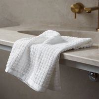 White textured towel draped over a marble countertop with a gold faucet in the background.
