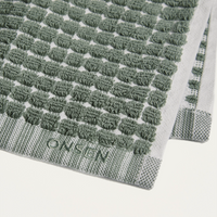 Green textured bath mat with 'Onsen' branding on a white background