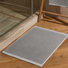 Gray doormat on a wooden floor next to a glass door