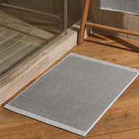 Gray doormat on a wooden floor next to a glass door