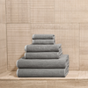 Stack of gray textured towels on a wooden floor with a wooden paneled wall in the background