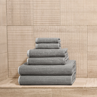 Stack of gray textured towels on a wooden floor with a wooden paneled wall in the background