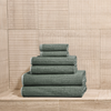 Stack of green towels against a wooden paneled wall