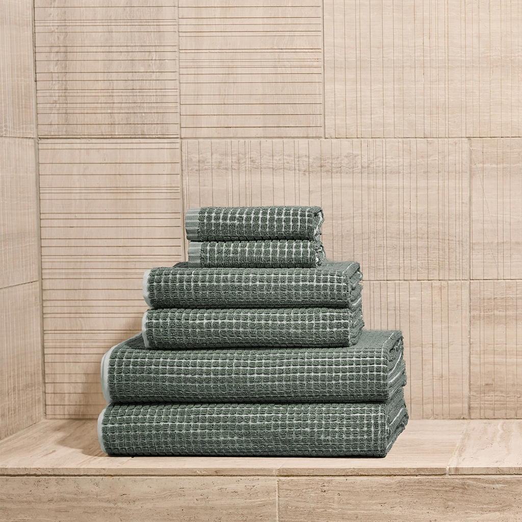 Stack of green towels against a wooden paneled wall