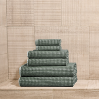 Stack of green towels against a wooden paneled wall
