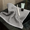 Gray textured towel on a dark surface with a tube of toothpaste and a toothbrush.