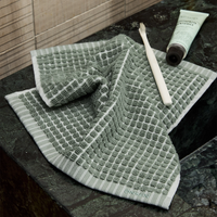 Green textured towel on a bathroom counter with toothpaste and a tube.