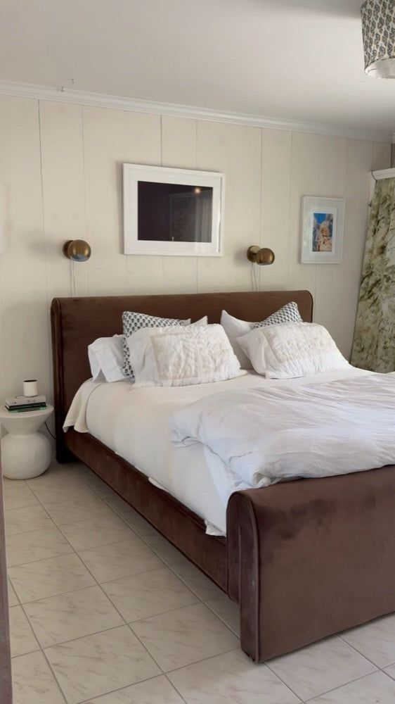 A freshly made bed in a bright, calm bedroom