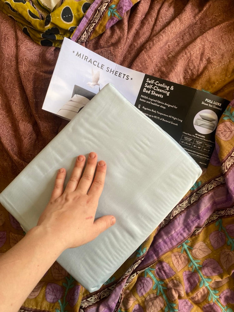 A hand resting on a folded Miracle Made sheet set
