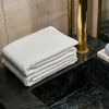 Stack of white towels on a black marble surface with a gold cylindrical object in the background.