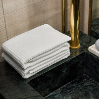 Stack of white towels on a black marble surface with a gold cylindrical object in the background.