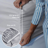 Person adjusting fitted sheet on a mattress with text indicating fit and stay put feature.